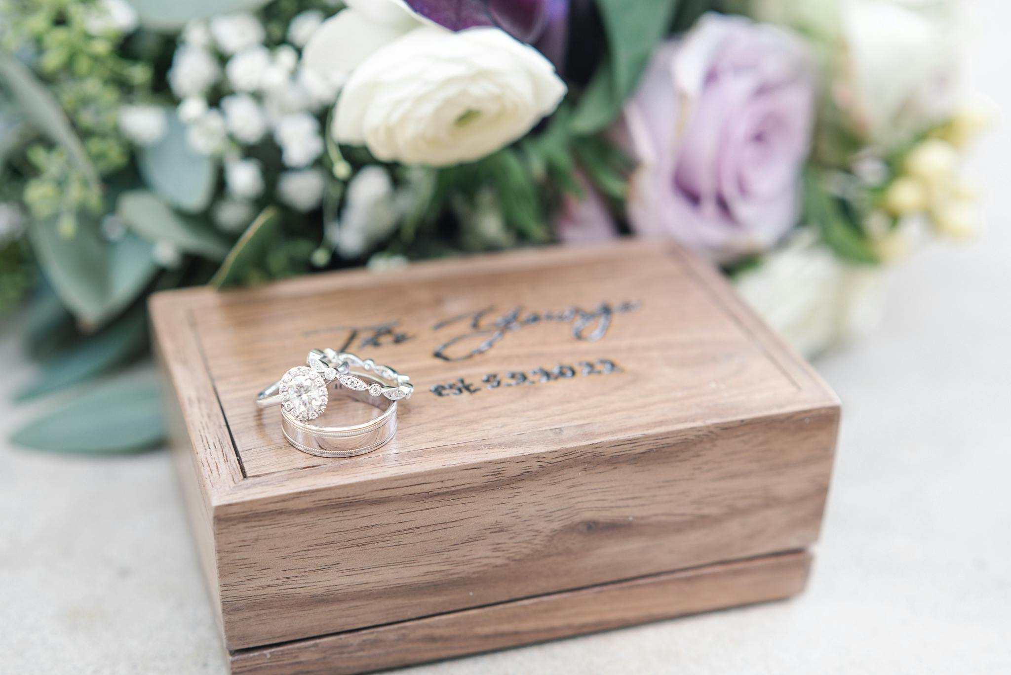 Weddings rings on a box in front of flowers